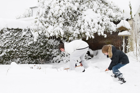 29565663 - father and son shoveling snow together in a garden