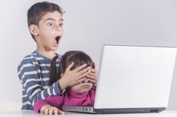 55052813 - little boy protects his sister from watching inappropriate content while using a computer. internet safety for kids concept. toned image with selective focus